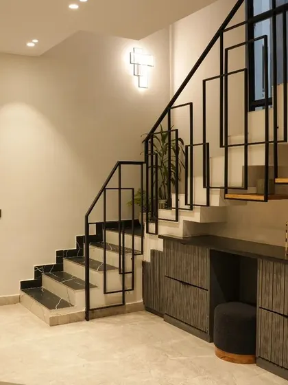The entrance of the Monochrome Oasis project features a captivating staircase with a sleek black metal frame in a geometric design.