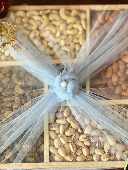 A close-up on the center of the dry fruit box, where the net is gathered and secured with a pearl accent.