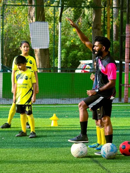 A coach stands on the ball while giving instructions, a classic pose that shows comfort and command on the field.
