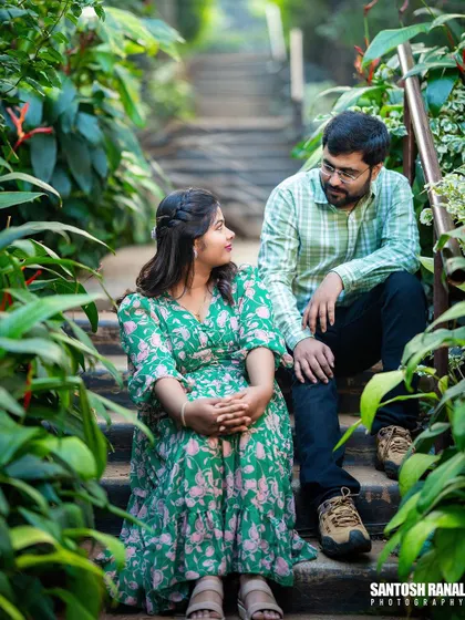 A sweet moment captured on a staircase surrounded by lush greenery.