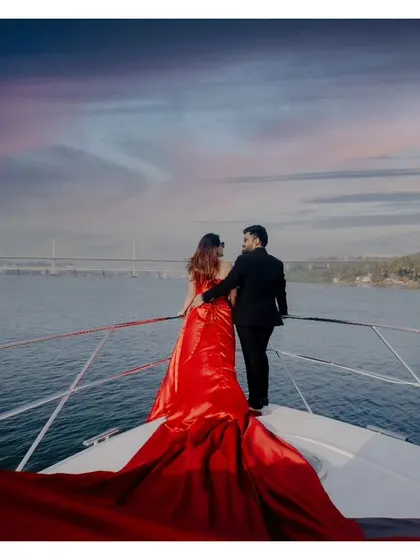 A wide, atmospheric shot of the couple looking out at the horizon from the yacht. The dramatic sky and the vastness of the sea create a powerful and epic romantic image.