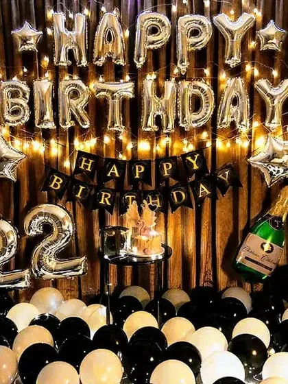 A classic black, white, and silver theme for a 22nd birthday. The setup includes a curtain backdrop with fairy lights, 'Happy Birthday' foil letters, and a cake stand.