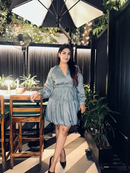 A dusty blue tiered mini dress with balloon sleeves. Paired with black pumps, it's a chic and playful look for an evening out.