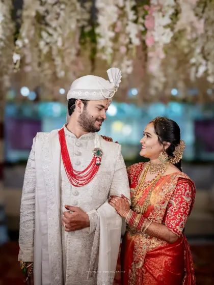 A beautiful portrait of the couple, the bride in a stunning red Kanjeevaram saree and the groom in an elegant white sherwani.