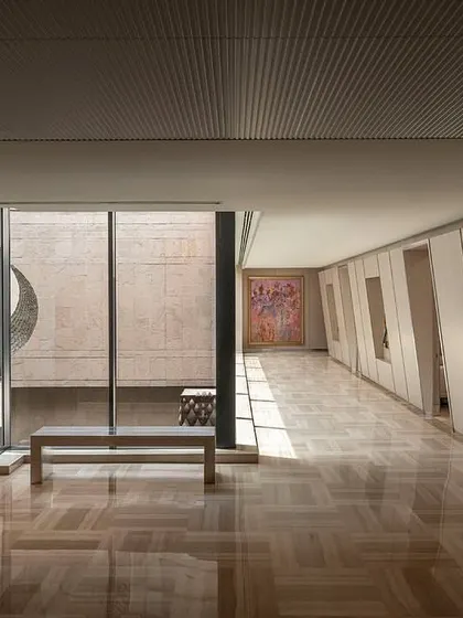 A long corridor on the directors' floor features wall niches for artwork and a large window overlooking the courtyard, blending circulation space with gallery-like moments.