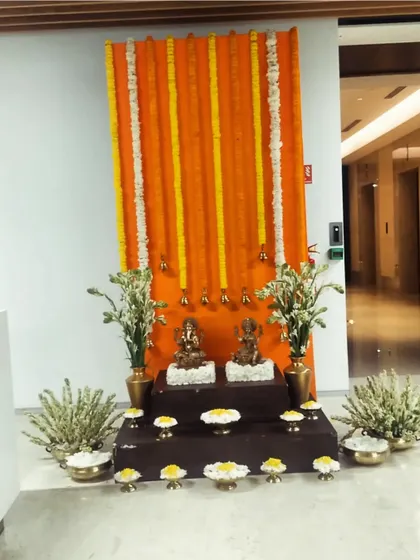 Another traditional setup for an office Diwali party. We created a backdrop of orange marigold garlands and placed idols on a tiered platform, surrounded by brass pots and fresh flowers.
