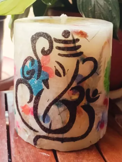 Celebrate Ganesh Chaturthi with our divine Ganesha Pillar Candle. This beautiful piece features a hand-drawn Ganesha design over a background of colorful pressed flowers.