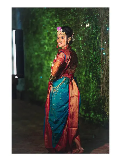 A full-length shot of the bride in her stunning blue and red Nauwari saree, showing off the elegance and grace of the traditional Maharashtrian bridal look.