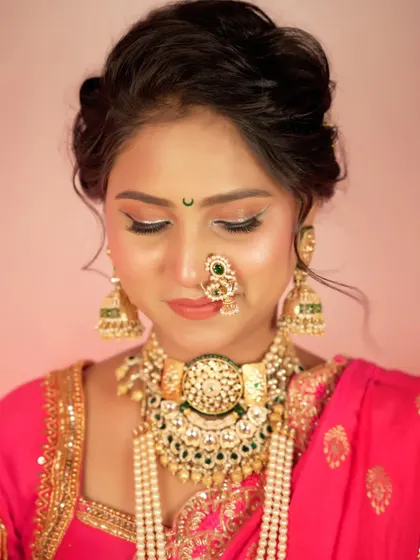 A close-up portrait focusing on the bride's flawless makeup and serene, downward gaze. This shot captures a moment of quiet elegance.