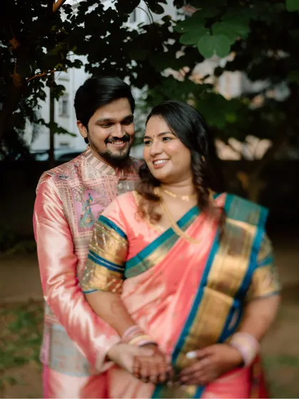A close-up portrait of a couple in a warm embrace, smiling at each other. The soft focus and natural lighting highlight their connection and the beauty of their traditional outfits.