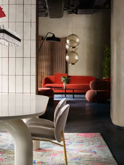 A glimpse from a dining area into a living room setup with a vibrant red sofa. The design uses sightlines and layered spaces to encourage exploration and discovery within the store.