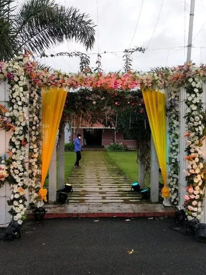 A beautiful floral entrance to a garden wedding, with yellow drapes adding a pop of color.