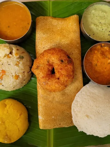 A customer's photo of our Mini Tiffin, showcasing the variety we offer. It includes a mini dosa, idli, vada, upma, and kesari, all served on a banana leaf.