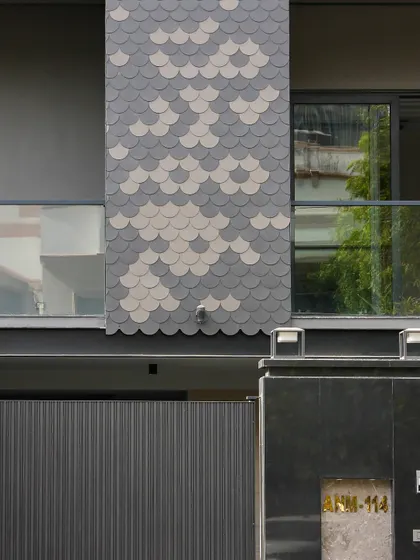 A close-up of the fish-scale tile pattern used on the Akashneem Marg project. This detail adds a unique, decorative element to the otherwise minimal and modern facade.