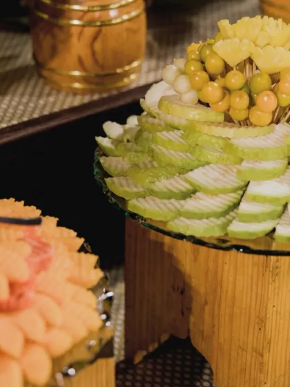 A variety of sliced fruits, including guava and papaya, beautifully arranged on tiered stands.