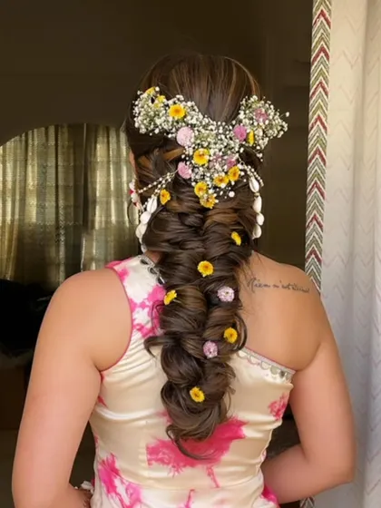 A beautiful, thick fishtail braid adorned with fresh yellow and pink flowers and a traditional passa. This is a perfect hairstyle for a Haldi or Mehendi ceremony.