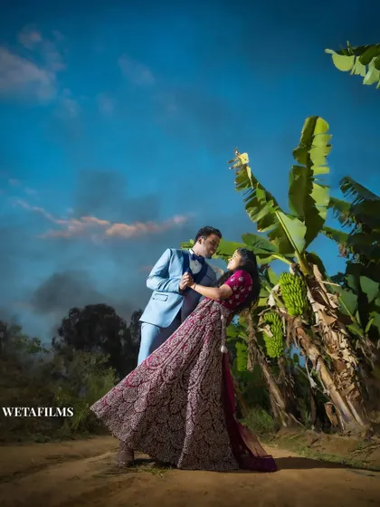 A dynamic pose under a brilliant blue sky. This pre-wedding photo captures a sense of joy and freedom, set against a vibrant natural backdrop.