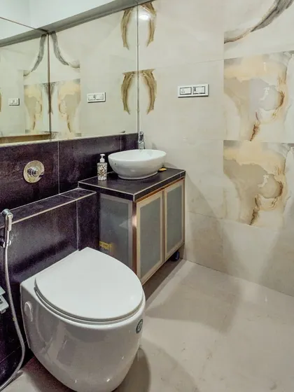 A stylish bathroom with a vessel sink and patterned wall tiles. The large mirror helps make the space feel bigger.