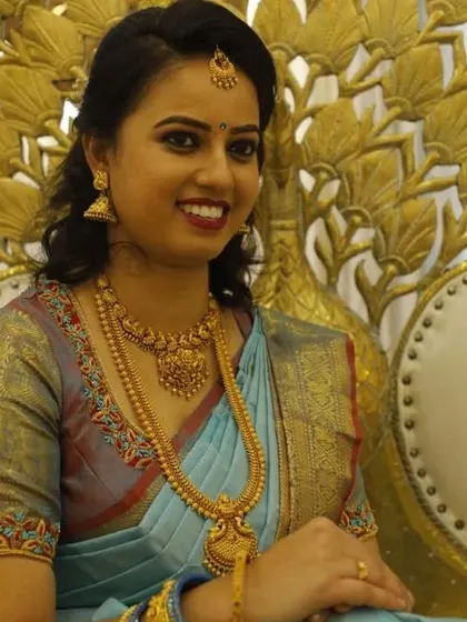 This client looks radiant for her event. The makeup is soft and pretty, with a classic red lip, paired with a simple and elegant hairstyle that complements her light blue saree.