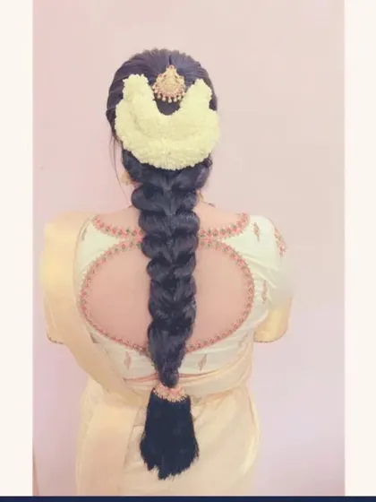 A classic thick braid with a neat puff, adorned with a semi-circular jasmine gajra and a gold hairpiece.
