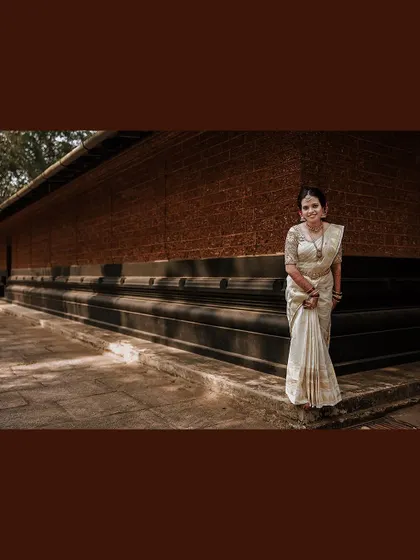 A wide shot of the bride standing against a traditional building.