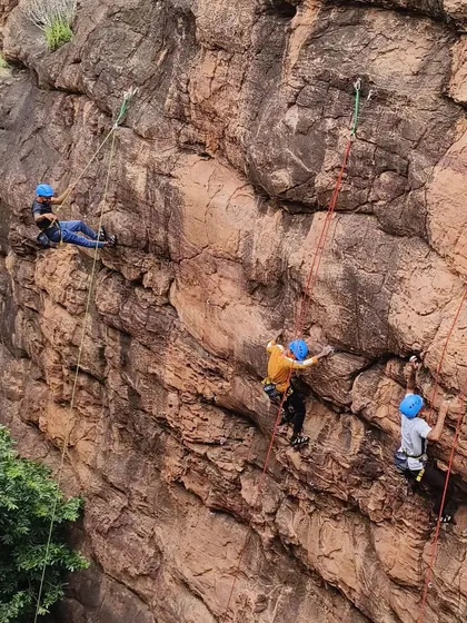 A view of multiple climbers at different stages of ascent on a large cliff face.