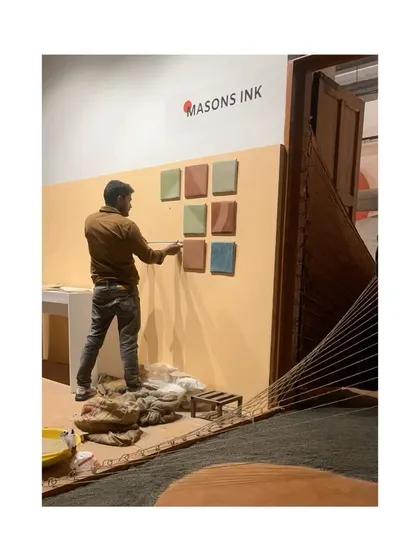An artisan arranging colorful Tadelakt tiles on the exhibition wall. This display showcases the beautiful range of natural pigments that can be used with lime plaster.