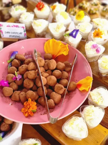 A platter of our dark chocolate truffles and mini cheesecakes, decorated with edible flowers. We use beautiful garnishes to make our desserts as visually appealing as they are delicious.