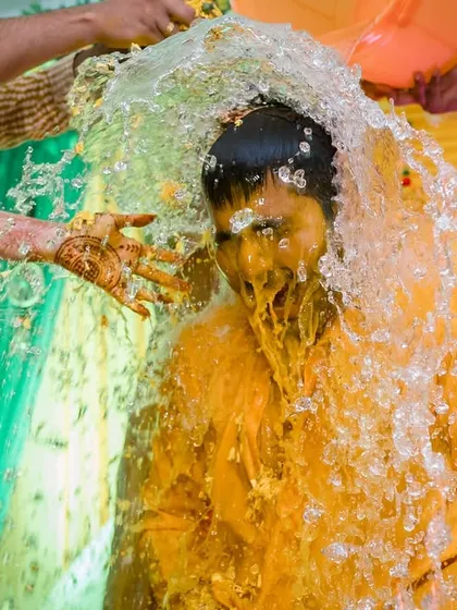 The ceremonial splash. A bucket of water is thrown on the groom, a refreshing and photogenic moment that adds to the Haldi fun.