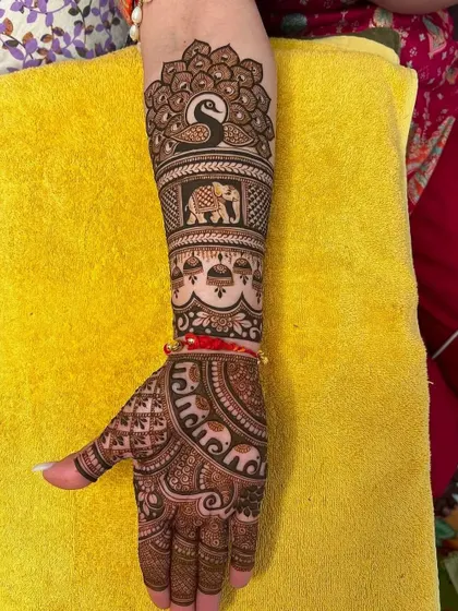 This design combines two favorite motifs: a peacock at the top and an elephant in the center of the arm. The jhumka (earring) details add to the festive look.
