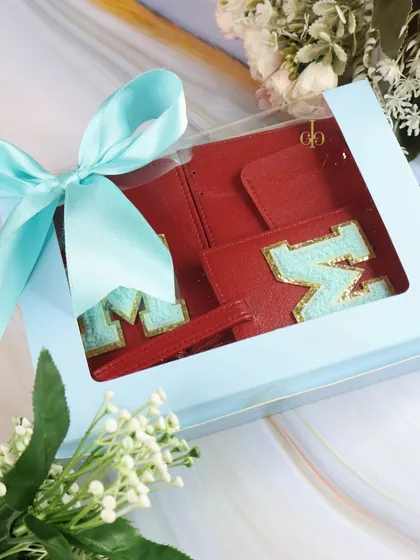 This travel combo in a light blue box is a great Rakhi gift for a brother or sister who loves to explore. The red monogrammed accessories add a pop of color.