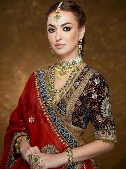 A mid-shot focusing on the luxurious velvet blouse and the exquisite, layered polki jewelry, conveying a sense of royal elegance.