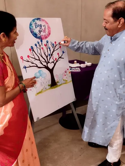 Family members joining in on the fun, casting their vote for 'Boy or Girl' on the thumbprint tree. It's a great way to get everyone involved in the excitement.