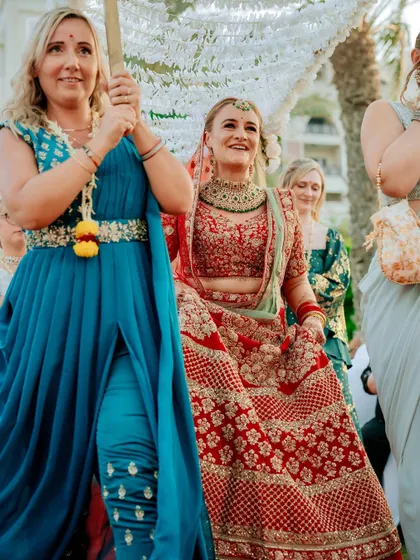 A close-up of the bride's happy expression as she walks towards the mandap, surrounded by her friends.