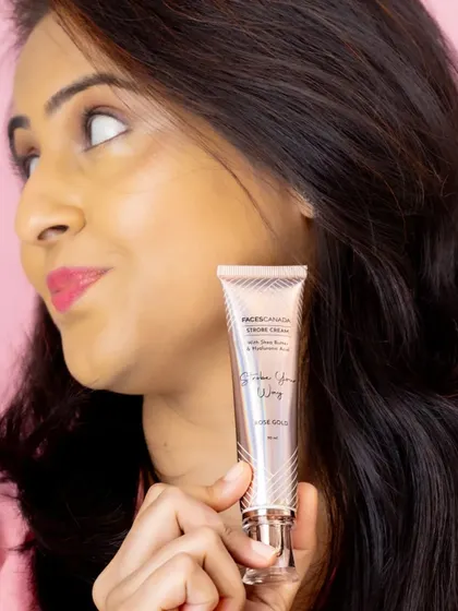 A candid-style lifestyle shot of a model holding the skincare product, looking away with a gentle smile.