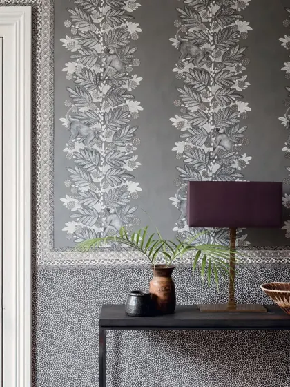 The 'Acacia' wallpaper from Cole & Son's Ardmore collection features playful monkeys within vertical stripes of foliage. This design brings a conversational and whimsical element to any room, blending nature with a structured pattern.