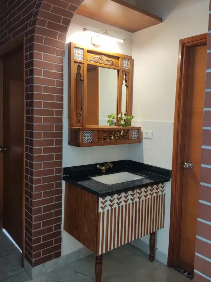 The complete vanity setup, showing the jharokha mirror paired with a custom wooden vanity. The hand-painted pattern on the cabinet doors adds a unique, artistic touch.