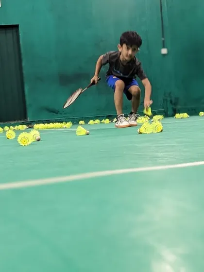 A young player helps collect shuttlecocks after a drill. We encourage discipline and teamwork as part of our coaching philosophy.
