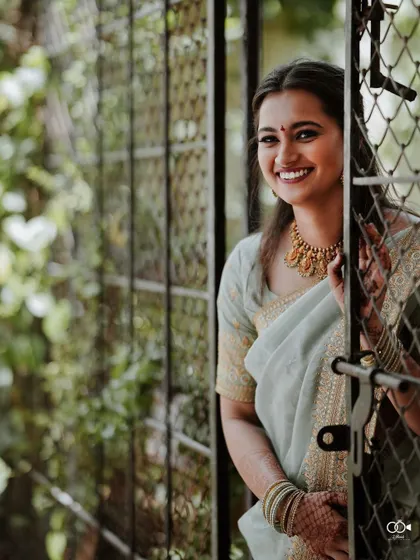 The bride smiles warmly as she looks out from behind a gate, a lovely and welcoming portrait.