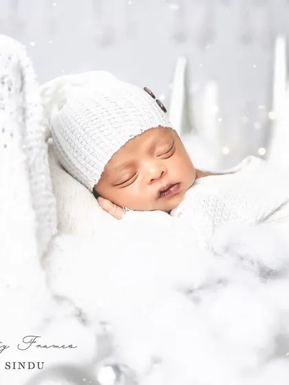 A close-up of a little snowflake, sleeping peacefully amidst a dreamy, white winter setup. My priority is always your baby's comfort and safety during these delicate sessions.