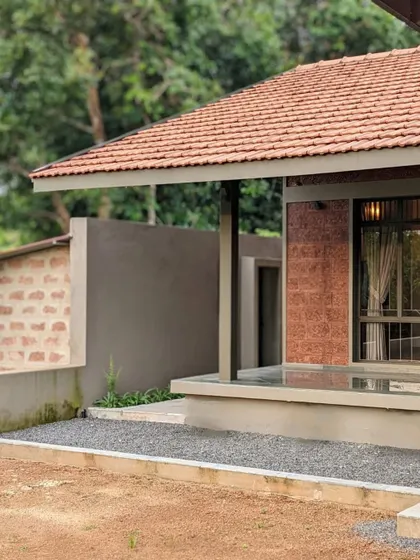 The exterior of a compact holiday home we designed in Mangalore. The design uses a combination of laterite stone, a cement-plastered base, and a traditional tiled roof.