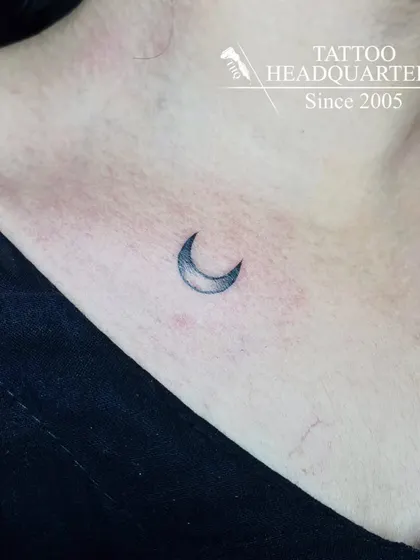 A small, shaded crescent moon tattoo on the collarbone, a simple and elegant choice.