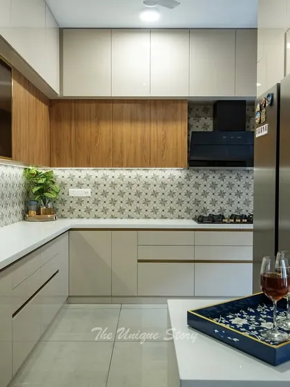 The "after" shot of a kitchen renovation, now featuring a modern design with beige and wood-finish cabinets, a patterned tile backsplash, and a functional breakfast counter.