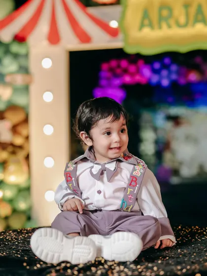 A big, happy smile from the birthday boy at his carnival party. The colorful background and his joyful expression perfectly capture the spirit of the day.