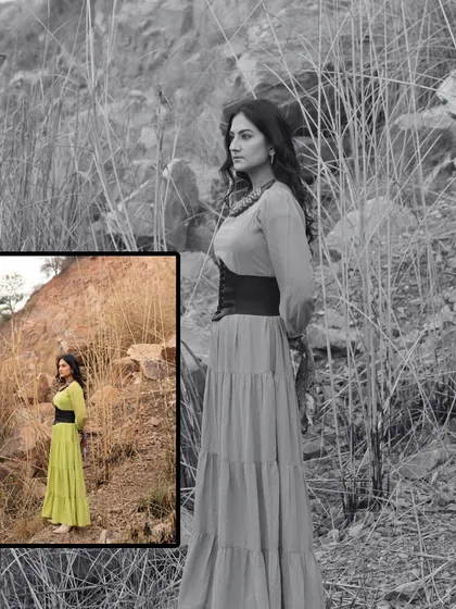 A full-length shot from the 'Boho Barren' portfolio. The tiered, long flowy dress paired with a corset-style belt creates a beautiful silhouette against the natural, rustic background.