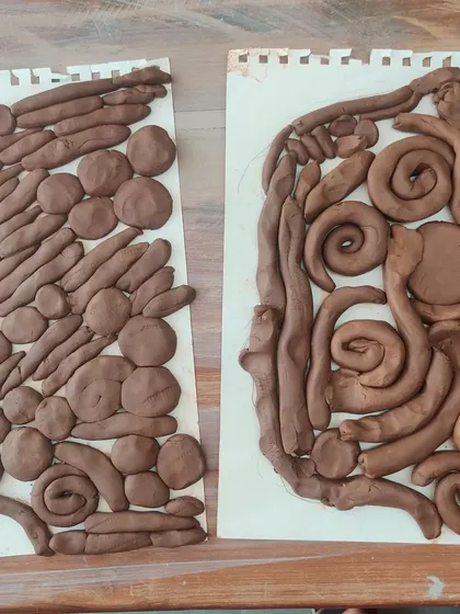 Two completed clay silhouettes sit side by side, each with its own unique pattern and style. It is amazing to see how different each child's interpretation is during our group art sessions.