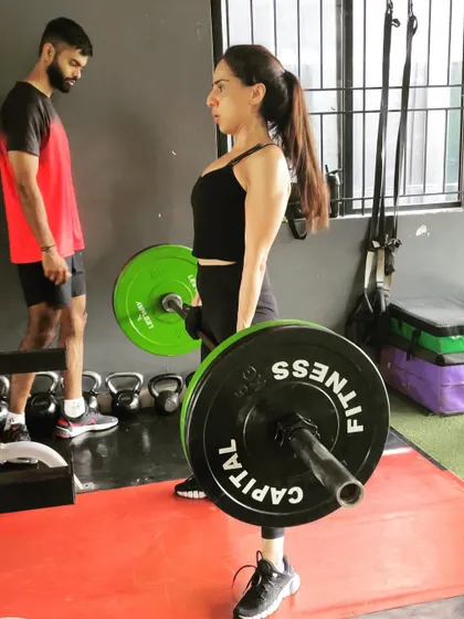 A client focuses on her deadlift form under the watchful eye of a trainer. We prioritize technique to ensure safety and maximize results.