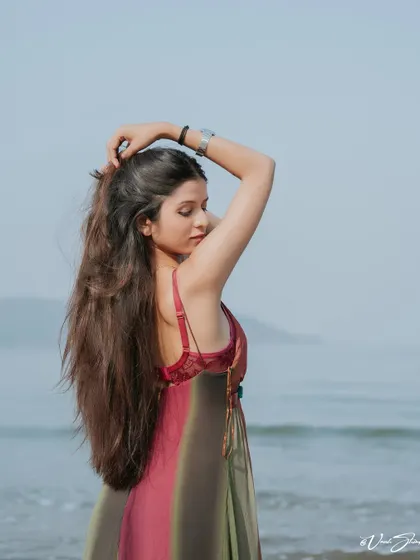 A side profile portrait against the sea. The focus is on the graceful lines of the pose and the soft light of the golden hour reflecting on the model.