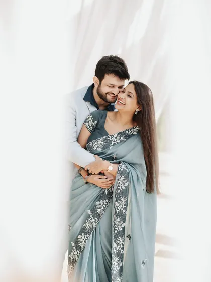 An elegant and tender portrait of a couple. The woman's beautiful saree and the soft, bright lighting create a timeless and graceful image that feels both modern and classic.