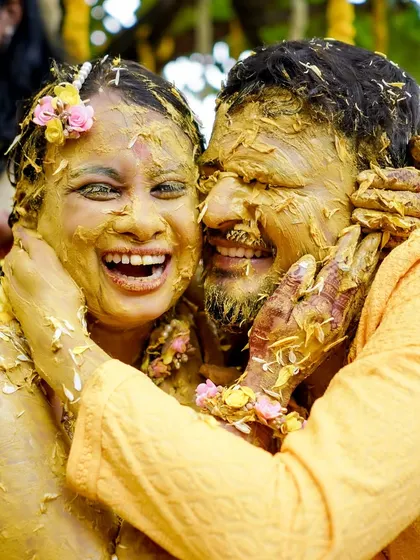 A candid shot of a couple laughing and embracing, covered in turmeric paste during their Haldi ceremony. These are the moments of pure joy I strive to create.